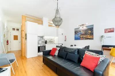 a living room with a black couch and a kitchen at GuestReady - Dolce experience in Porto in Porto