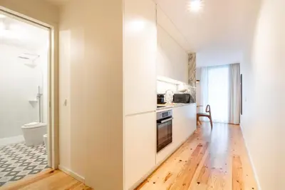 a kitchen with white cabinets and a wooden floor at Luxurious Studio Retreat in Porto by LovelyStay in Porto