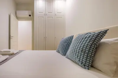 a white bed with blue pillows on top of it at Art Deco 32 Luxury 2BR Apartment Downtown Metro AC in Porto