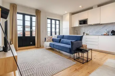 a living room with a blue couch and a kitchen at Art Deco 42 Luxury 2BR Apartment Downtown Metro AC in Porto