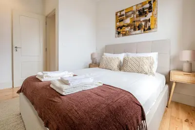 a bedroom with a large white bed with towels on it at Art Deco 42 Luxury 2BR Apartment Downtown Metro AC in Porto