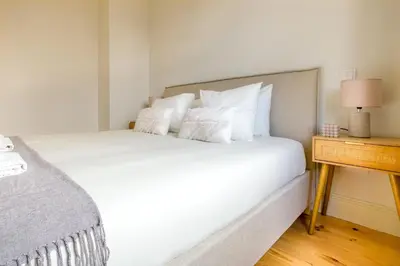 a bedroom with a white bed with a night stand at Art Deco 41 Luxury Apartment Downtown Metro AC in Porto