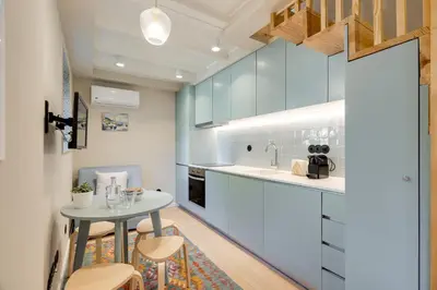 a kitchen with white cabinets and a small table at Figueirôa Four Houses by DA'Home in Porto