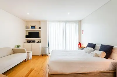 a bedroom with a large white bed and a couch at GuestReady - Homely escape near Bolhão in Porto
