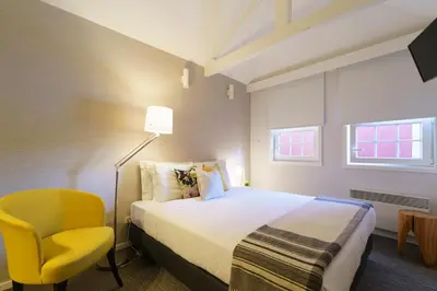 a hotel room with a bed and a yellow chair at Stay in Apartments Ribeira 24 in Porto