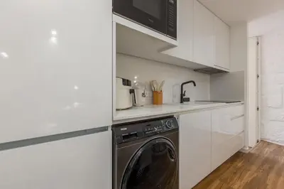 a kitchen with a washing machine in a white kitchen at OPO Ribeira II in Porto