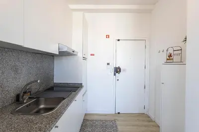 a white kitchen with a sink and a refrigerator at ApartmentsPorto - Boavista Delight Studio in Porto