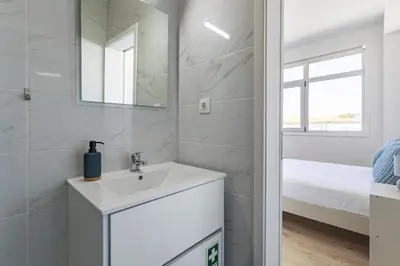 a white bathroom with a sink and a mirror at ApartmentsPorto - Boavista Delight Studio in Porto