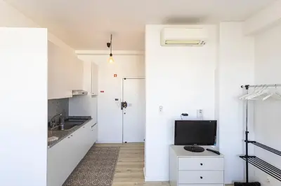 a white kitchen with a sink and a television at ApartmentsPorto - Boavista Delight Studio in Porto