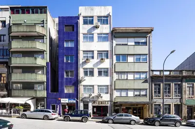 a tall building with cars parked in front of it at ApartmentsPorto - Boavista Delight Studio in Porto