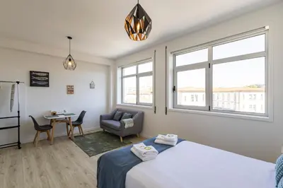 a bedroom with a bed and a chair and a table at ApartmentsPorto - Boavista Delight Studio in Porto