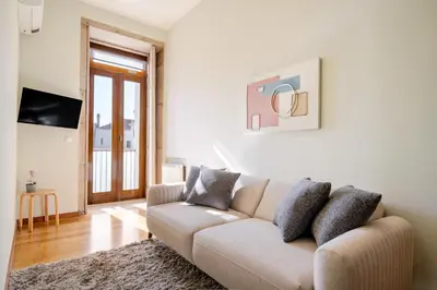 a white living room with a couch and a television at HostWise - Stylish Flat with Balcony in Porto
