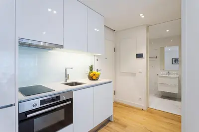 a white kitchen with a sink and a stove at Studio w/ Terrace, Pool & Gym | Antas by Host Wise in Porto