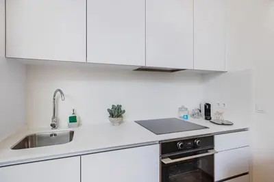 a kitchen and dining room with white walls and wooden floors at Saldanha Boho Duplex in Porto