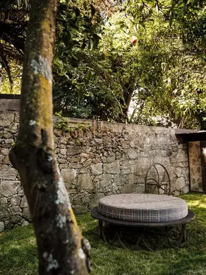 a table and chair sitting next to a stone wall at Malmerendas Boutique Lodging in Porto