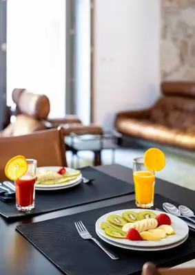 a table with two plates of fruit and two glasses of juice at Malmerendas Boutique Lodging in Porto