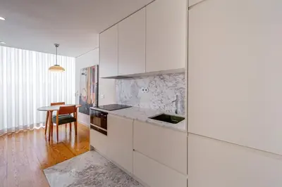 a kitchen with white cabinets and a wooden table at 5daMaria - Porto Center in Porto