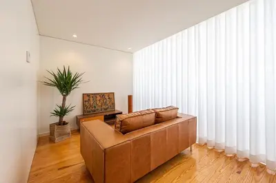 a living room with a brown couch in front of a window at 5daMaria - Porto Center in Porto