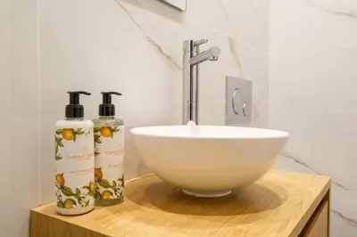 a bathroom with a sink and two bottles on a counter at Art Deco 21 Luxury 2BR Apartment Downtown Metro AC in Porto
