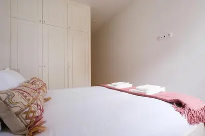 a white bed with a blanket on top of it at Art Deco 21 Luxury 2BR Apartment Downtown Metro AC in Porto