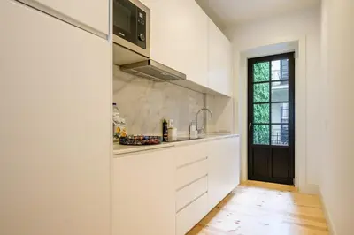 a kitchen with white cabinets and a black door at Art Deco 21 Luxury 2BR Apartment Downtown Metro AC in Porto