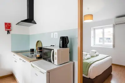 a small kitchen with a microwave and a bed at GuestReady - Invicta Porto Guest House in Porto