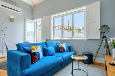 a blue couch in a living room with windows at Bonfim Garden Apartment Near Metro & City Center in Porto