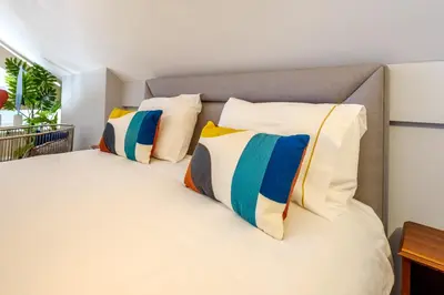 a bedroom with a white bed with colorful pillows at Bonfim Garden Apartment Near Metro & City Center in Porto