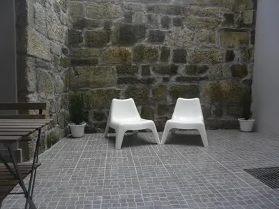 two white chairs sitting next to a brick wall at Your Place Porto II in Porto