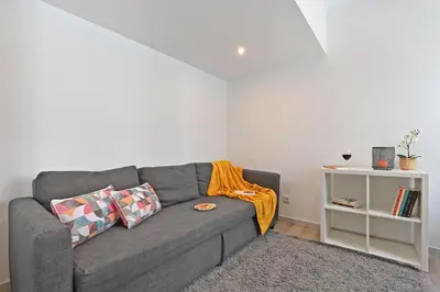 a living room with a gray couch with orange blanket at Crystal Palace House - T2 - D13 in Porto