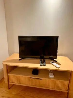 a flat screen tv on a wooden stand with remote controls at Porto Suites in Porto