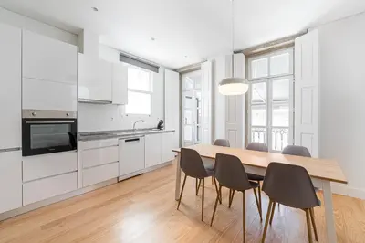 a kitchen with white cabinets and a wooden table and chairs at GuestReady - RNB Apartments in Porto