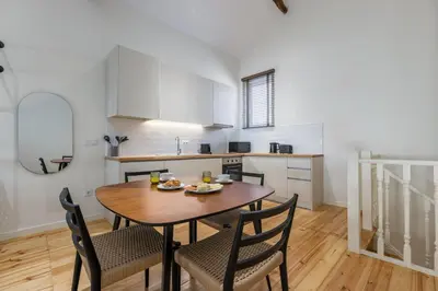 a kitchen and dining room with a wooden table and chairs at Albertina Carlos Alberto by Aspasios in Porto