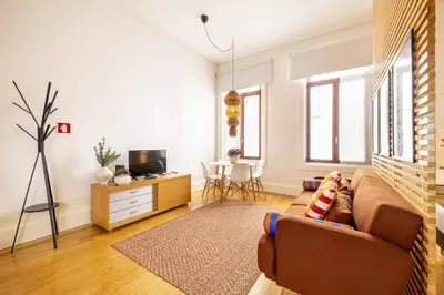 a living room with a couch and a tv at Porto Ribeira Flat in Porto