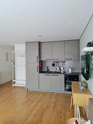 a kitchen with white cabinets and a wooden floor at Campanhã - Studio A in Porto