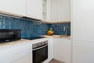 a kitchen with white cabinets and blue tiles at HostWise - Modern Flat in Boavista in Porto