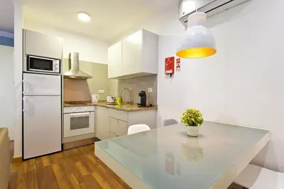 a kitchen with a table and a white refrigerator at APOSENTUS - The First in Porto