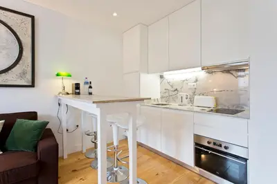 a kitchen with white cabinets and a counter top at APOSENTUS - Porto's Charming Apartment in Porto