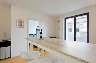 a kitchen with a wooden counter with two white chairs at APOSENTUS - Porto's Charming Apartment in Porto