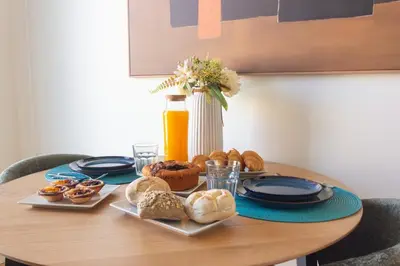 a table with plates of food and a bottle of orange juice at ORM - Cedofeita II Apartment in Porto