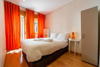 a bedroom with a large bed with orange curtains at O'Porto Main Street St Catarina 1 in Porto