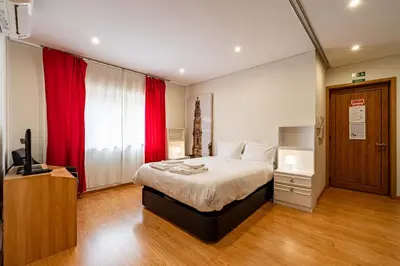 a bedroom with a bed with red curtains and a television at O'Porto Main Street St Catarina 2 Studio Apartment in Porto