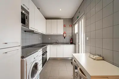a kitchen with white cabinets and a washer at O'Porto Main Street St Catarina 2 Studio Apartment in Porto