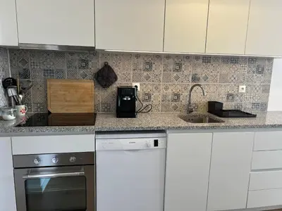 a kitchen with a refrigerator and a living room at O Alecrim in Porto