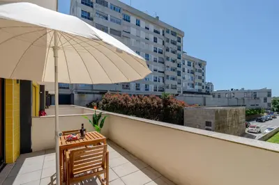 a table and an umbrella on a balcony with a building at Host Wise Stylish Studio with Garage in Porto