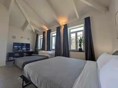 a bedroom with two beds and two windows at Castelo River View - NEW in Vila Nova de Gaia