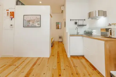 a kitchen with white cabinets and a wooden floor at Marques 1243 by Vacationy in Porto