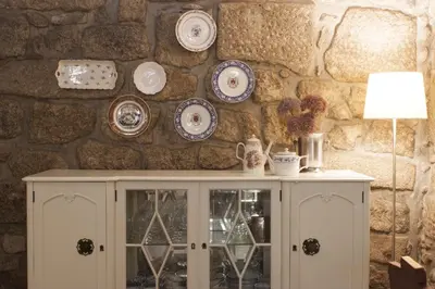 a white cabinet with plates on a stone wall at Being Porto Hostel in Porto