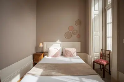 a bedroom with a bed with two pillows and a chair at Being Porto Hostel in Porto
