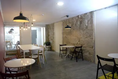 a restaurant with tables and chairs and a stone wall at O2 Hostel in Porto